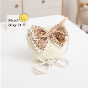 Detail of a beige straw bag for girls with a large brown floral bow and white lace trim