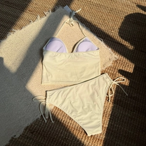 Detailed flat lay of a high-waisted beige bikini set featuring halter neck and side ties