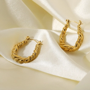 Detailed shot of gold-plated stainless steel twisted hoop earrings on white silk fabric