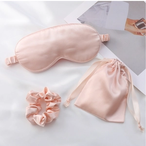 Detail view of pink satin sleep set with eye mask, scrunchie, and drawstring storage bag