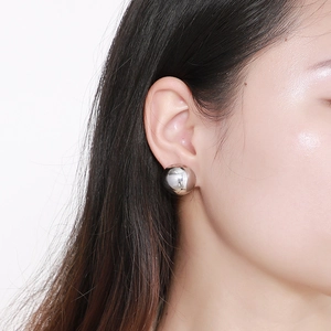 Polished silver hollow sphere stud earrings shown on model for size and style reference