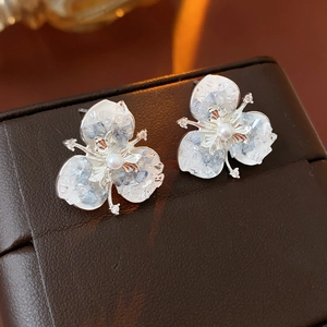Macro view of crystal flower stud earrings with pearl center on brown leather