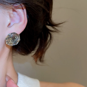 Close-up of elegant multifaceted grey crystal stud earring worn on model's ear