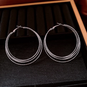 Macro shot of silver multi-layered hoop earrings on black velvet jewelry organizer