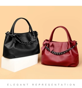 Detail of elegant black and burgundy large tote bags with chic bows and metal chain accents