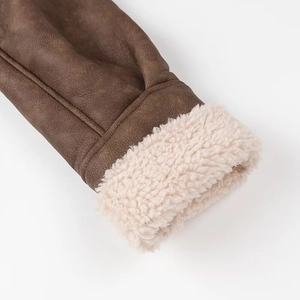 Close-up of brown faux suede jacket sleeve with thick cream shearling lining texture