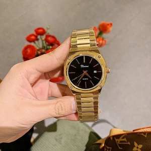 Close-up of golden quartz watch with black dial and date display held in hand