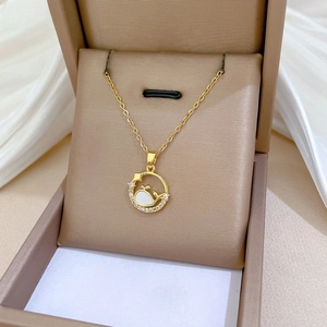Detailed macro of gold whale tail circle pendant with white shell and zircon inlay