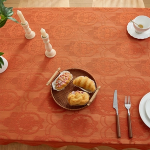 Macro shot of orange-red jacquard tablecloth with vintage floral pattern and thick texture