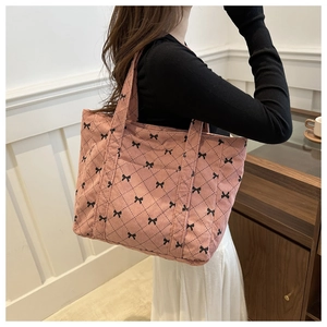 Detail view of pink corduroy shoulder bag with black diamond pattern and bow detail