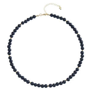 Detailed macro view of black volcanic stone beads with gold spacers and heart charm clasp