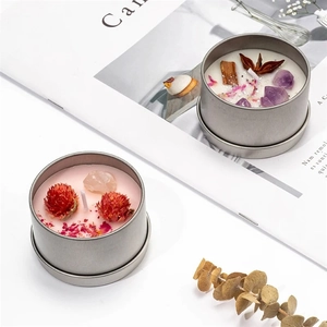 Top view of handmade scented soy wax candles in tins with dried flowers and crystals
