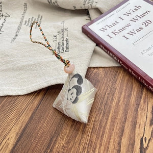 Detailed view of silk-textured panda zongzi charm with colorful braided cord and beads