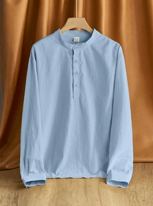 Detail shot of light blue linen shirt fabric texture and Henley neck on a wooden hanger