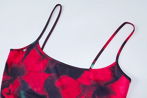 Gros plan sur les fines bretelles et l'imprimé floral rouge et noir de la robe
