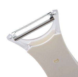 Detail of sharp stainless steel serrated blade on a white handheld fruit vegetable peeler