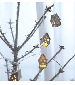 Detail of wooden house LED string lights glowing with warm yellow light on white branches