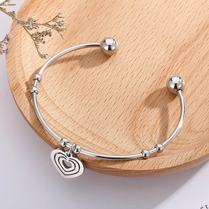 Detailed macro view of a silver heart pendant bracelet on a wooden display tray