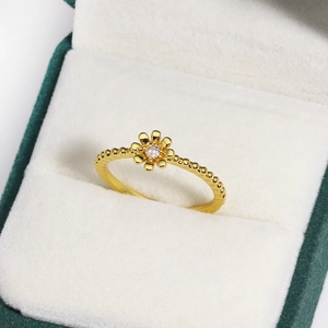 Detail eines goldenen Blumenrings mit Zirkon und Perlenband auf grünem Samtkasten