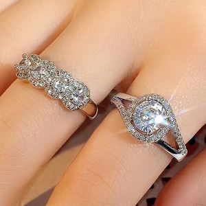 Macro detail of silver halo ring and four-stone row ring on finger with sparkling gems