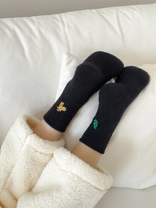 Detail of warm black fleece socks with cute giraffe and leaf embroidery on ankles