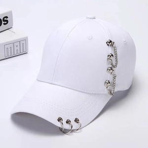 Detail view of white baseball cap featuring silver metal rings and side chain decorations