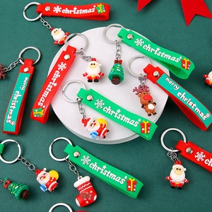 Christmas silicone keychains with Santa and reindeer charms on green textured surface