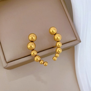 Elegant gold curved stud earrings with graduated beads on beige jewelry display