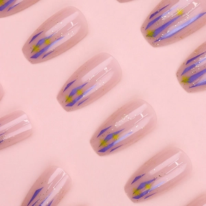 Pink press-on nails with purple geometric lines, yellow stars and gold glitter accents