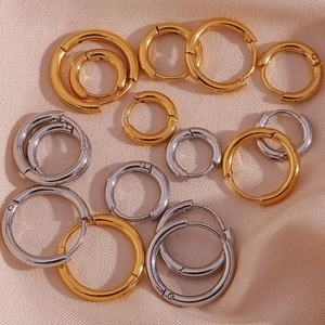 Détail macro de boucles d'oreilles créoles polies or et argent sur tissu en soie