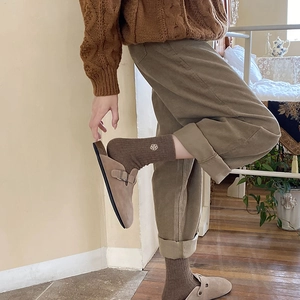 Close-up of brown knitted warm socks with flower embroidery and corduroy trousers