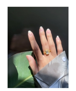 Macro detail of gold textured ring featuring a large rectangular crystal on finger