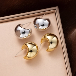Detailed view of polished gold and silver waterdrop earrings on a jewelry tray