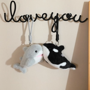 Cute plush dolphin and whale keychains with woven ropes hanging on a wall hook