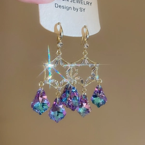 Close-up of gold star earrings with sparkling crystals and iridescent teardrop tassels