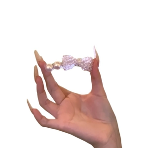 Elegant pearl and sparkling purple bow hair clip for women shown on a hand for scale