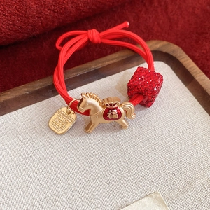 Détail de l'élastique à cheveux rouge avec pendentif cheval doré et breloque chance