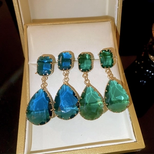Detail of drop earrings with royal blue and emerald green crystals in gold metal settings