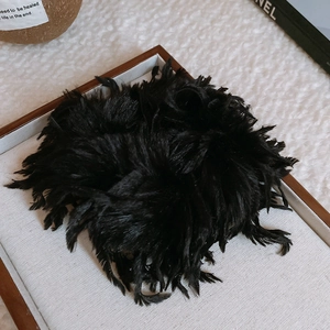 Détail d'un chouchou en plumes noires duveteuses sur un plateau d'exposition blanc