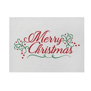 Close-up of linen placemat featuring Merry Christmas print with red stars and green scrolls