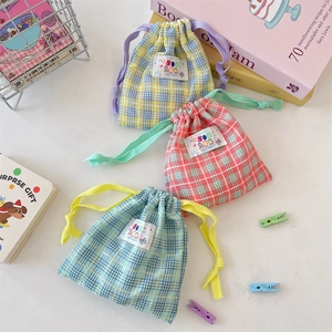 Three colorful checkered drawstring pouches in yellow, pink and blue for travel storage