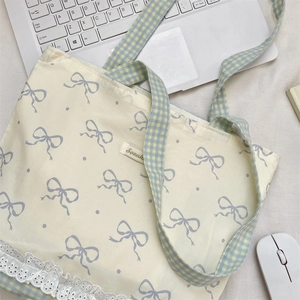 Close-up of canvas tote bag with bow prints, plaid straps and lace edge on the desk