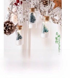 Close-up of glass wishing bottle lights with mini Christmas trees and warm LED glow