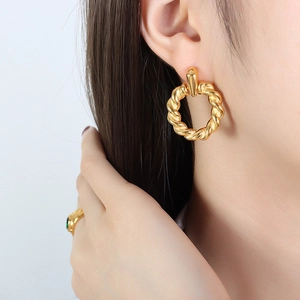 Twisted gold hoop earrings in stainless steel, elegant vintage style worn by model