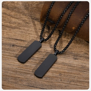 Detail of two black rectangular stainless steel military pendants on a box chain