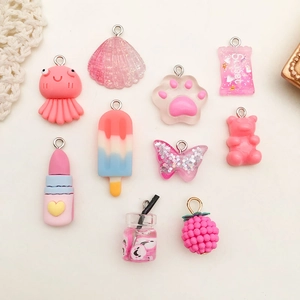 Flat lay of pink resin DIY charms in octopus, shell, cat paw, and candy bag shapes