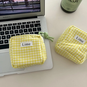 Detailed close-up of yellow plaid canvas pouch with a Lime tag on a laptop keyboard