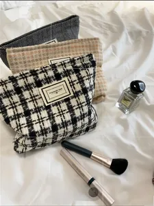 Detailed view of three checkered tweed toiletry bags with textured fabric and zipper closure