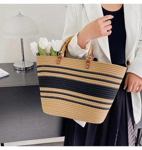 Detail of woven tote bag with bamboo handles and chic black beige striped pattern