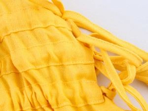 Detail of yellow smocked fabric texture and tie shoulder straps on vacation maxi dress